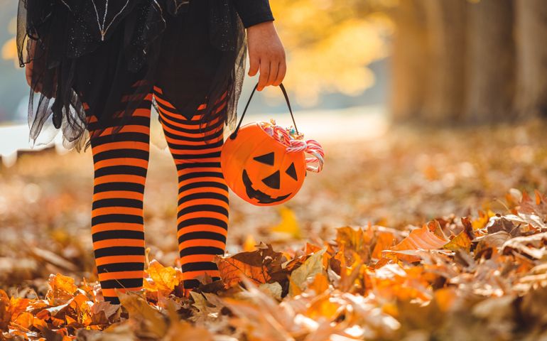 Little girl in witch costume having fun outdoors on Halloween trick or treat