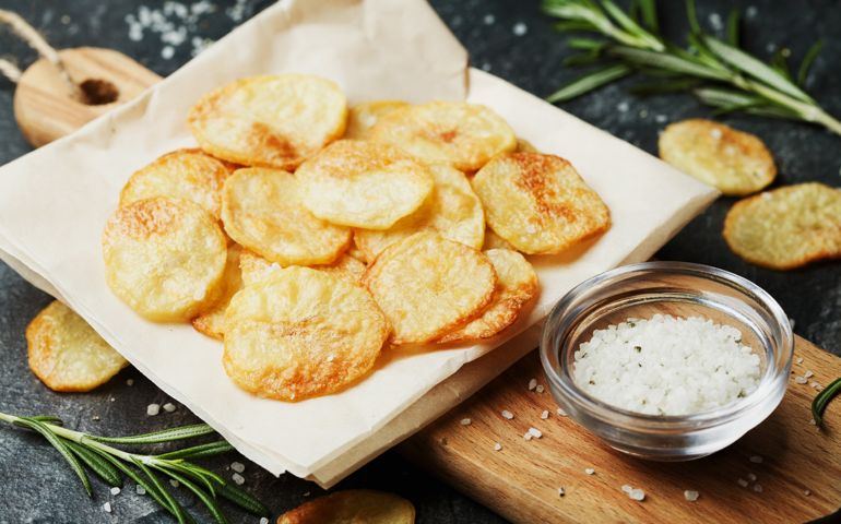 Homemade potato chips with sea salt and herb on wooden cutting board