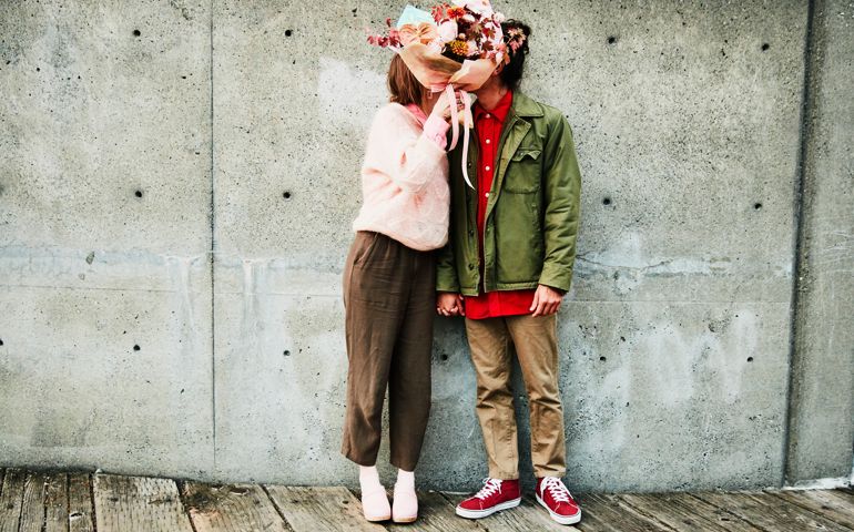 Portrait of couple kissing while hidden behind bouquet of flowers