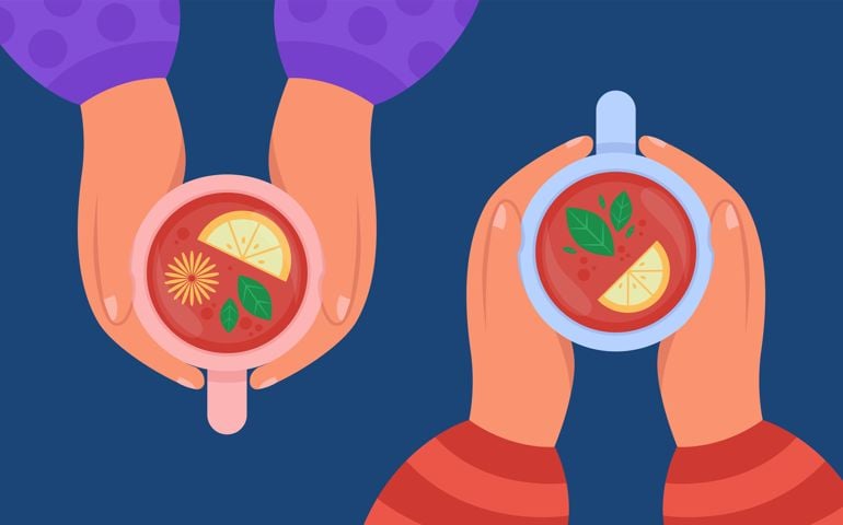 Top view of hands holding cups of drink with lemon.