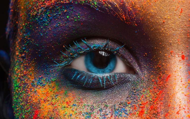 Crop of female eye with colorful make up. Beautiful fashion model with creative art makeup. Abstract colourful splash make-up. Holi festival