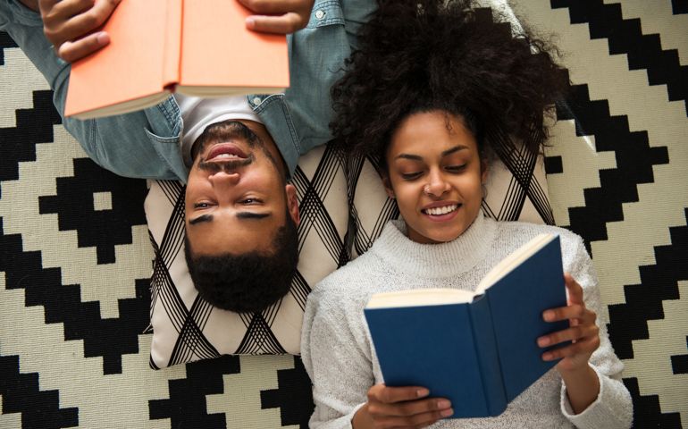 African american couple lying on the floor and reading books.