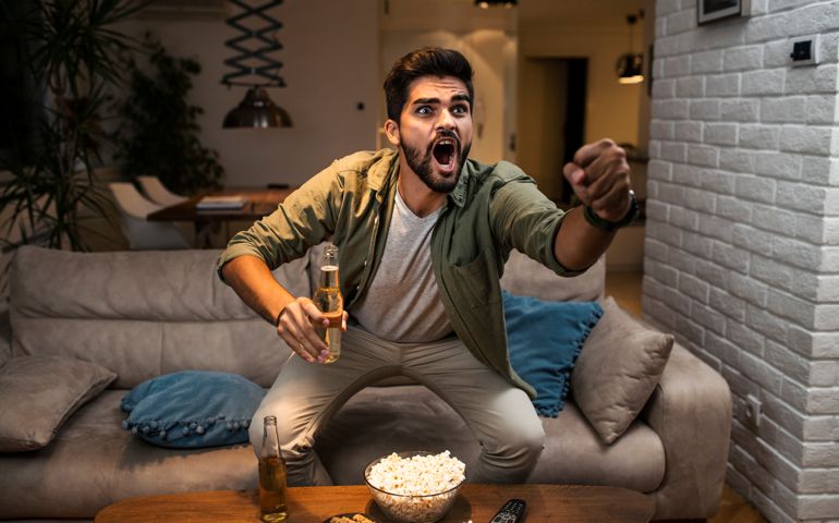 The young man is watching a sports game on TV