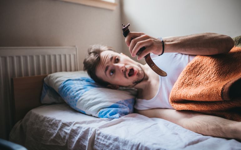 A young man looking at his wristwatch after sleeping in too long