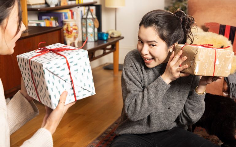 Woman shakes Christmas present to check what is inside.