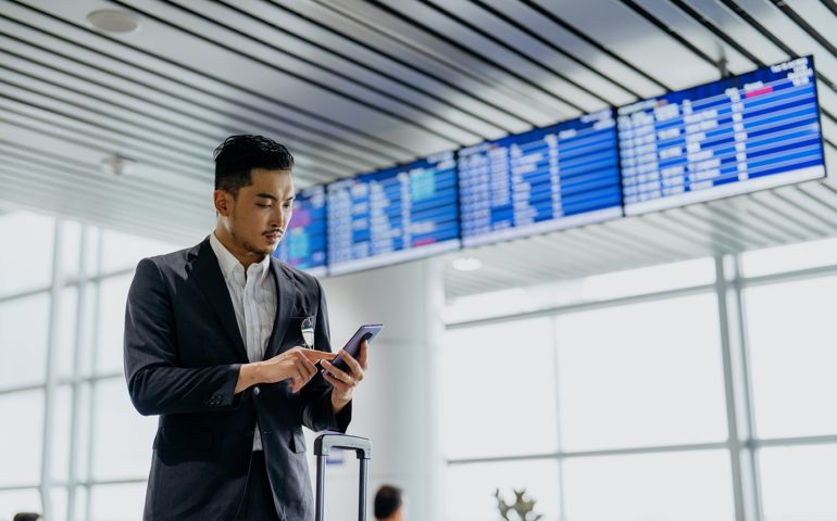 Image of an Asian Chinese businessman traveller using smartphone in airport terminal