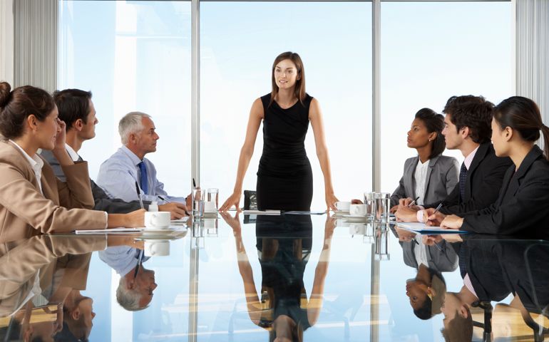 Group Of Business People Having Board Meeting Around Glass Table.