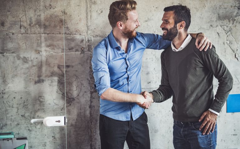 Happy businessmen greeting each other in the office.