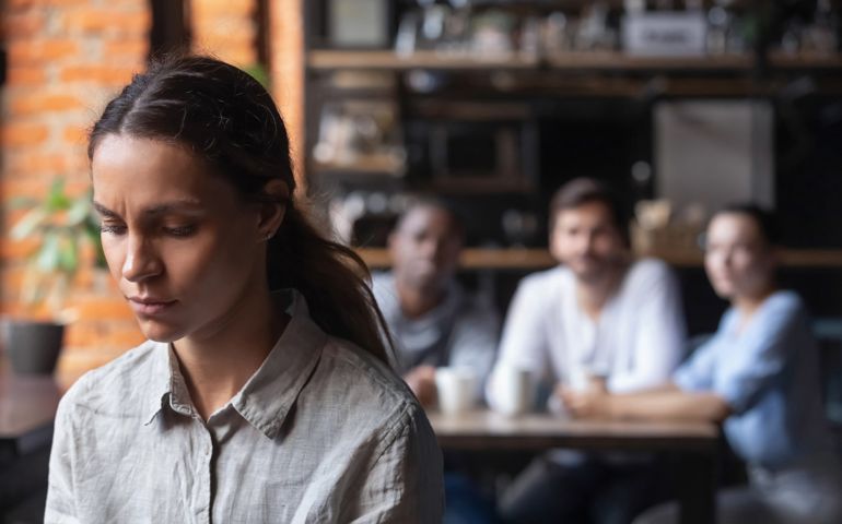 woman suffering from bullying, discrimination, excluded girl having problem with bad friends, feeling offended and hurt, sitting alone in cafe,
