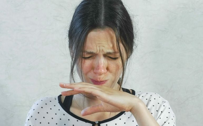 Emotions from the acid on the girl's face. Brunette woman eating sour tangerine and wincing