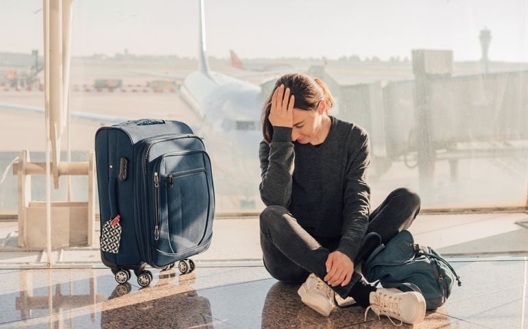 Sad (tired) woman sitting in the airport - missed or cancelled flight concept.