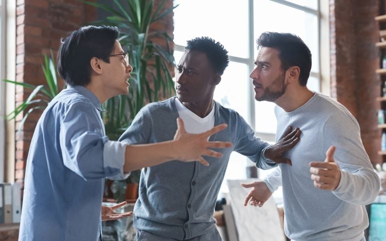 man breaking up an argument between two other people
