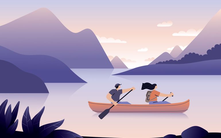 Couple canoeing on a lake surrounded with beautiful landscape.