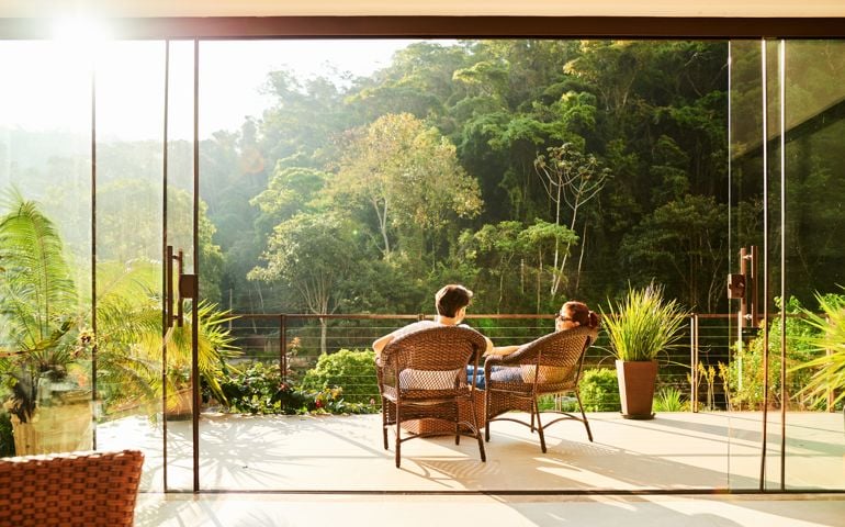 Rear view of a couple relaxing in the chairs at hotel balcony