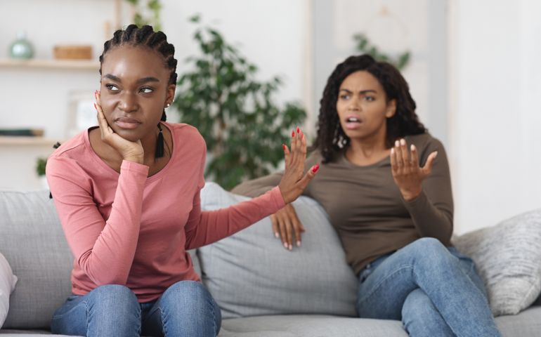 Annoyed woman showing stop gesture to her scolding girlfriend.
