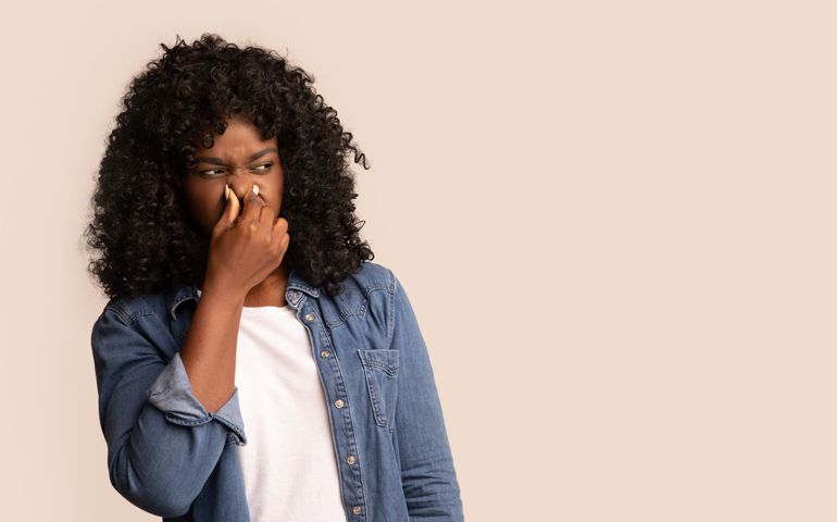woman closing nose with fingers, feeling unpleasant scent