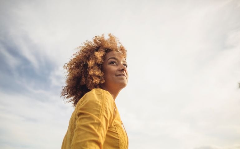 Low angle portrait of beautiful woman against sky
