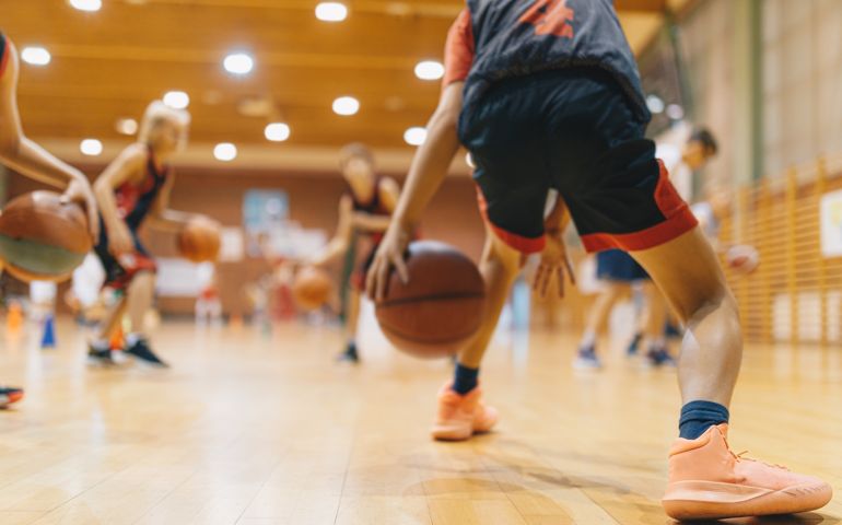 Young Basketball Player on Practice Session. Youth Basketball Team Bouncing Balls on Sports Court.