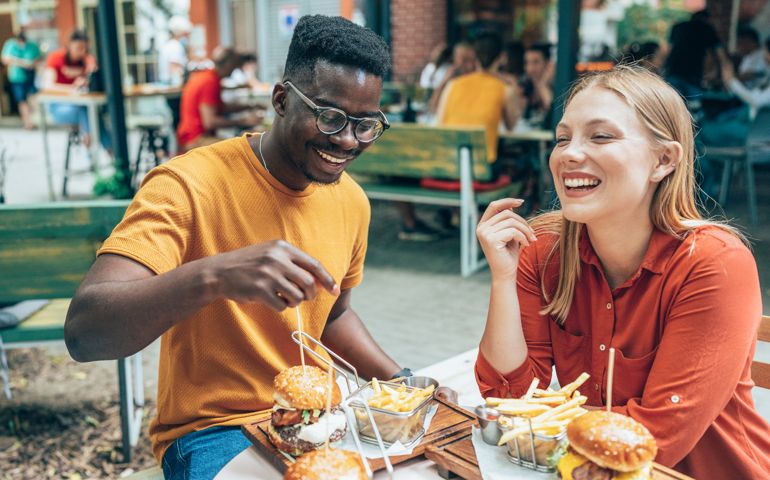 Friends eating burgers and fries and have fun in outdoor restaurant