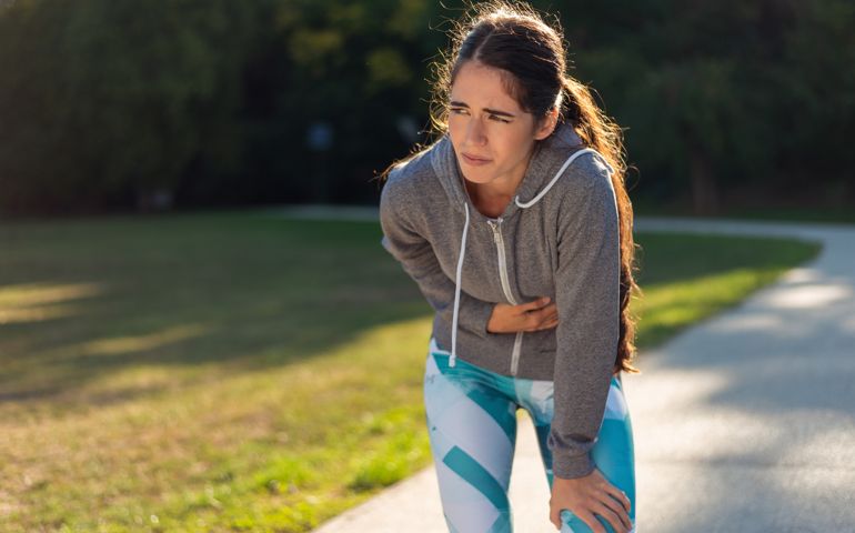 Young sporty woman has stomachache in park