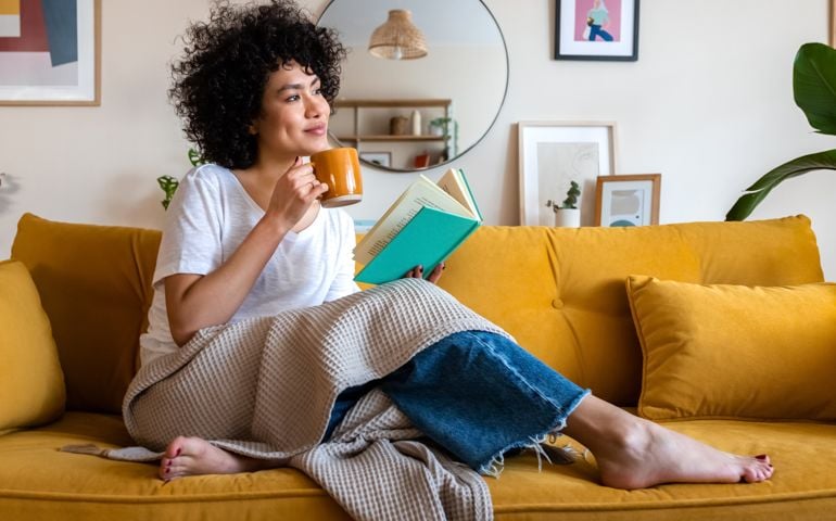 Pensive relaxed woman reading a book at home,
