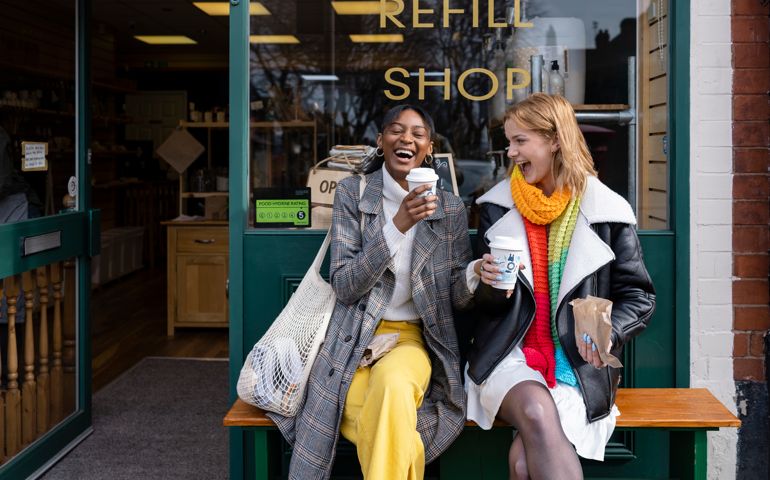 Two friends sitting outside a store that promotes sustainable living in the North East of England.