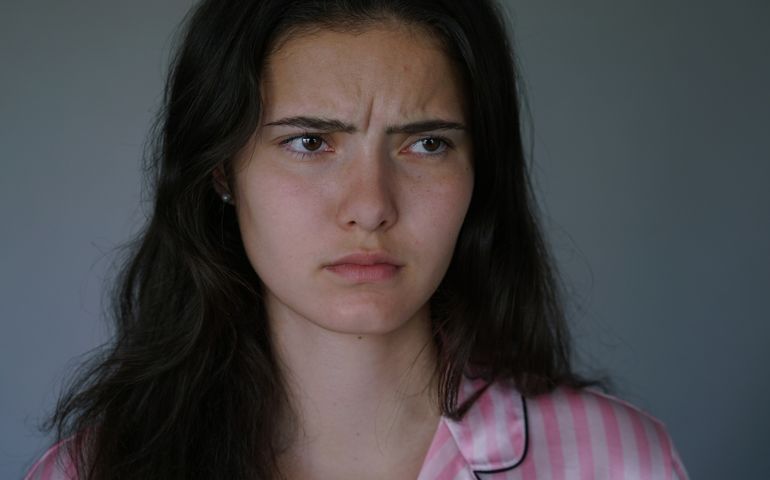 Portrait of young unhappy teen girl with disheveled hairstyle. Young woman face with sad pensive look.