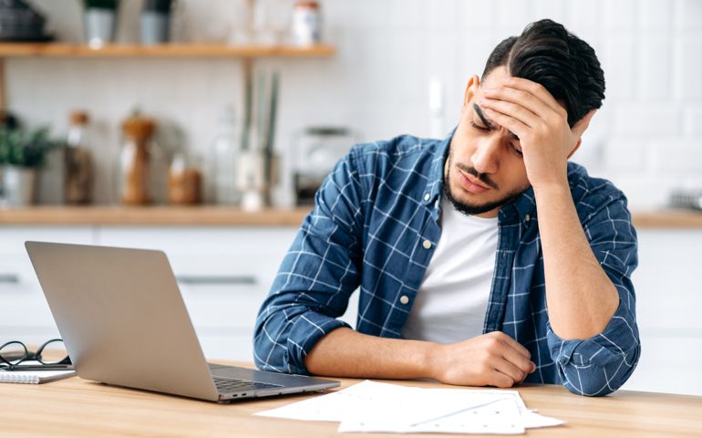 Tired worried sad guy, sit at a desk, looking tired and stressed,