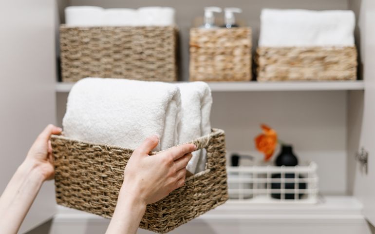 Clean fresh towels neatly folded and placed in closet organizer box.