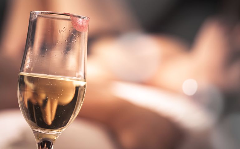 Champagne glass with a lipstick and sensual woman in a background