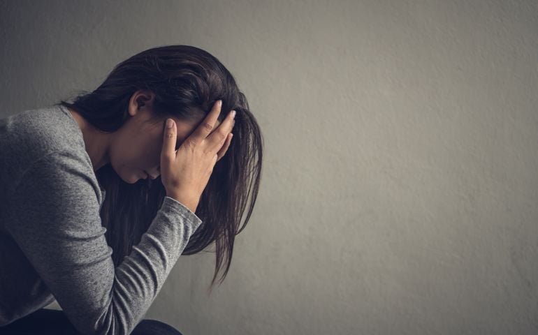 Depressed woman sitting on a chair in dark room at home. Lonly , sad, emotion concept.