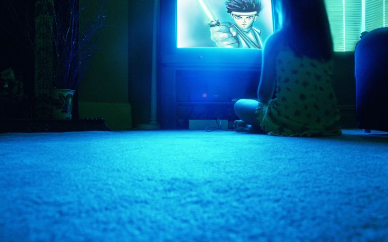 Young girl (8-10) sitting on floor watching television, rear view