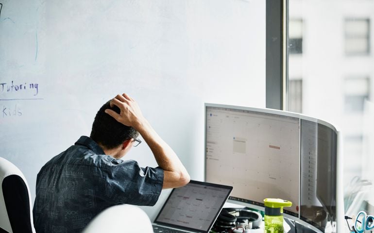 Engineer scratching head while looking at calendar on computer monitor in virtual reality lab