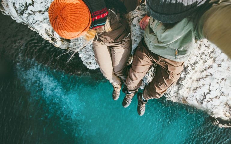 Man and Woman sitting together above sea on cliff Travel happy emotions Lifestyle concept