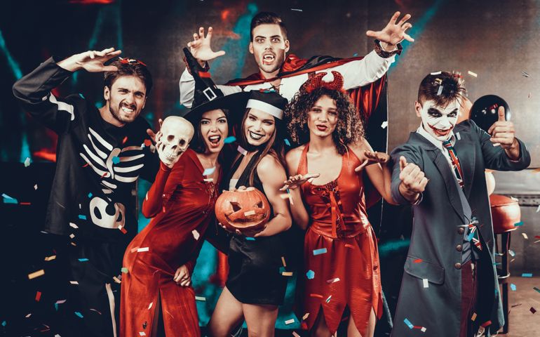 Portrait of Young Smiling People in Scary Costumes. Group of Young Happy Friends Wearing Halloween Costumes having Fun Together and posing for Group photo in Nightclub.