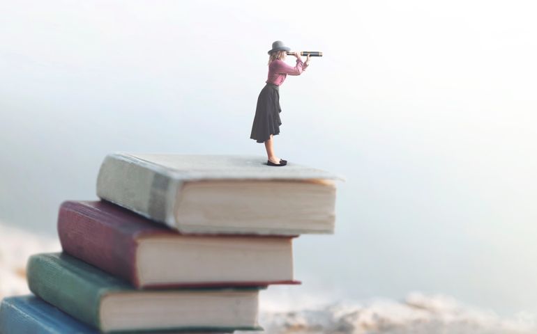 miniature woman looks at the infinity with the spyglass on a scale of books