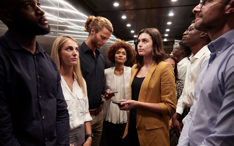 Work colleagues stand waiting together in an elevator at their office