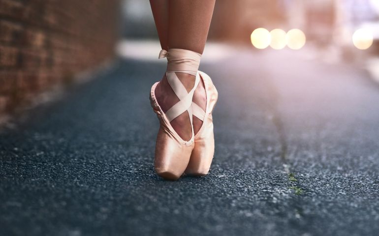 Cropped shot of a ballet dancer standing on tiptoes against an urban background