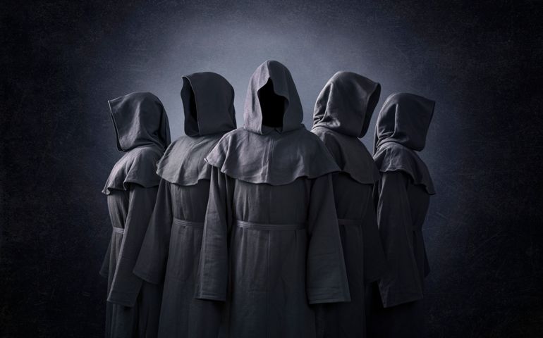 Group of five scary figures in hooded cloaks in the dark
