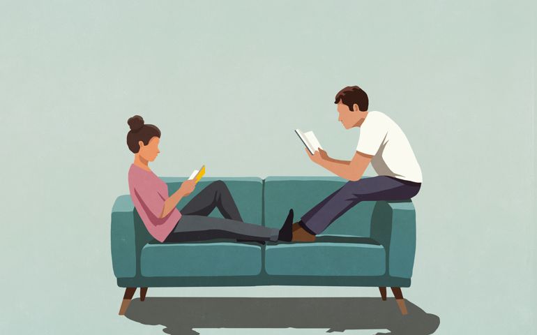 Couple reading books on sofa