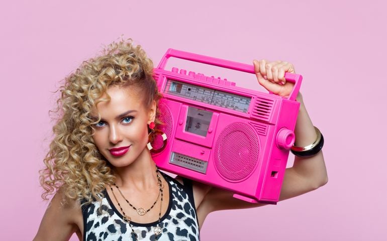 Happy woman in 80's style outfit holding boom box