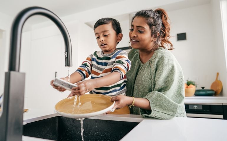 Mom and child washing dishes together