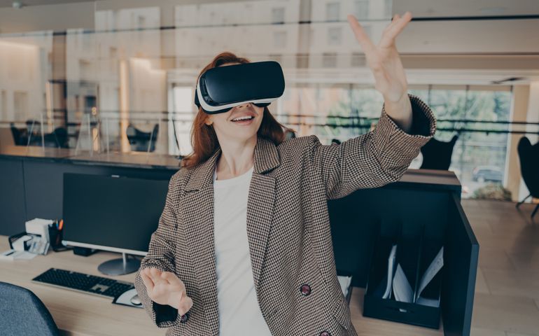 Female office worker using virtual reality headset to visualize and browse files at work