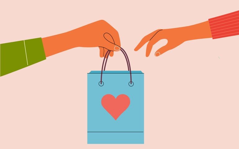 Male hand holding craft paper gift Bag with red heart. Man gives a valentine's day gift to a woman.