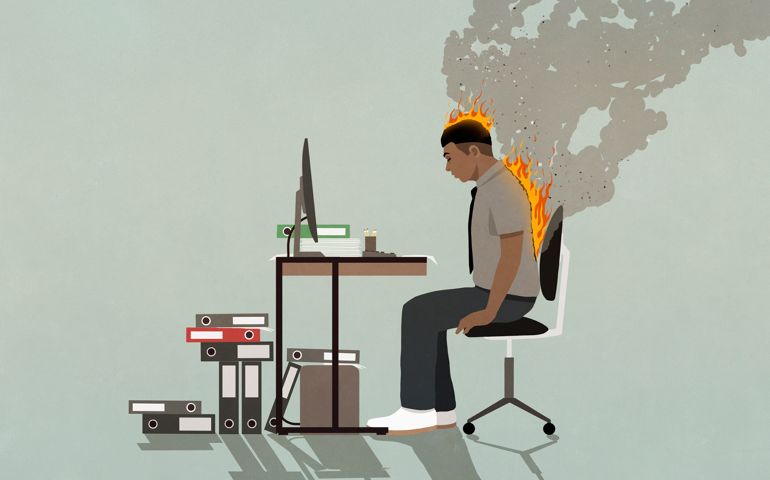 Businessman on fire working at computer at office desk