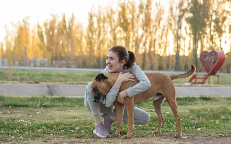Woman smiling in the park with stray dog