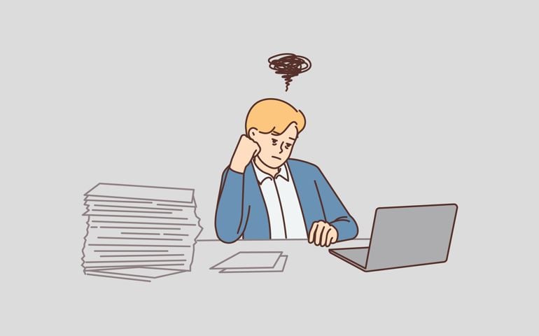 Distressed unhappy businessman sit at desk in office overwhelmed with work. Stressed male employee overwork at workplace on computer.