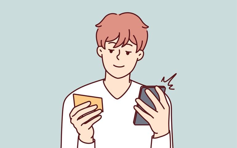 Happy young man paying online on cellphone with credit card.