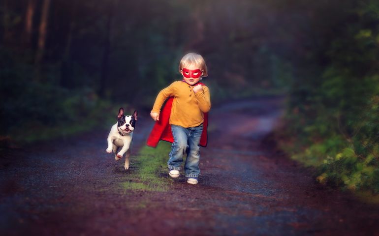 Child dressed up like a super hero with sidekick french bulldog puppy