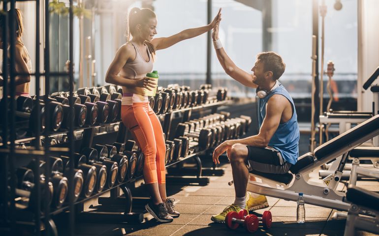 Happy athletic couple giving each other high five after finishing sports training in a gym.